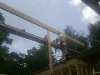Carpenter setting a ridge beam over a new addition frame — Ice Dam Removal by Roofing Brothers in Gulf Shores