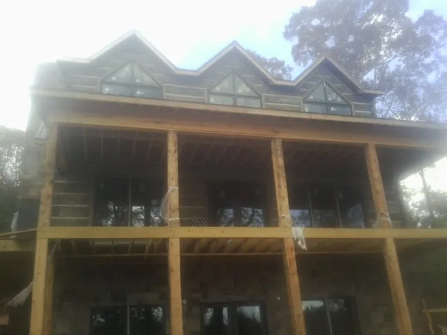 Dormers and porch framing on a large log home under construction — Roof Coating work by our crew in Gulf Shores