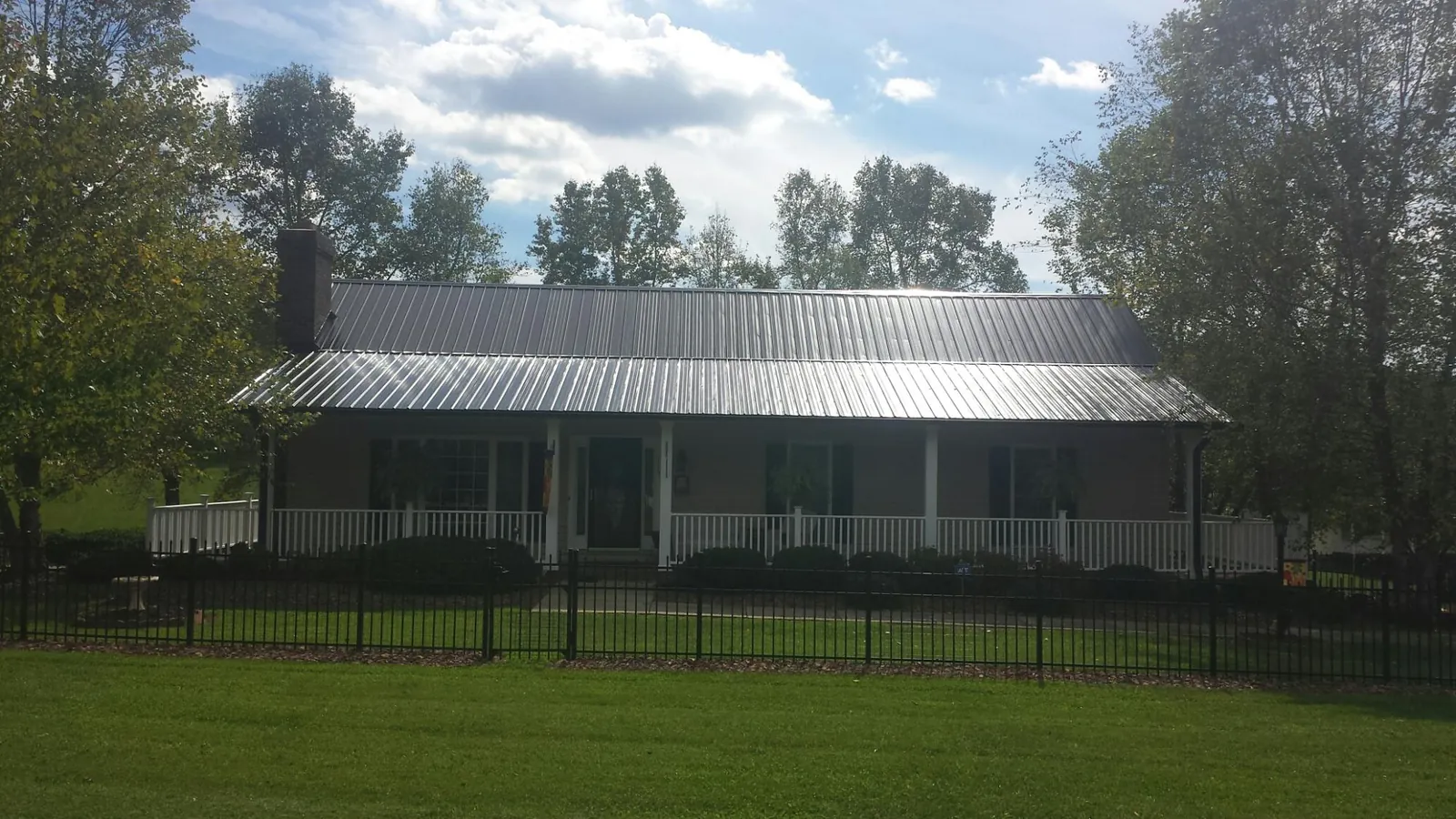 Gray metal roof on a brick ranch with a full width front porch — Gutter Guard Installation work by our crew in Gulf Shores