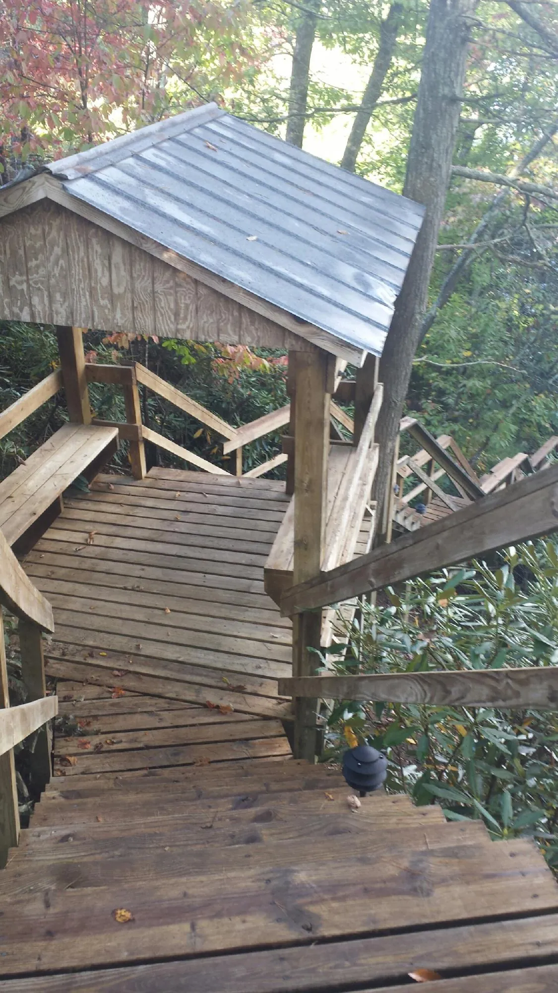 Metal roofed shelter over wooden steps on a wooded walkway — Skylight Repair & Installation work by our crew in Gulf Shores
