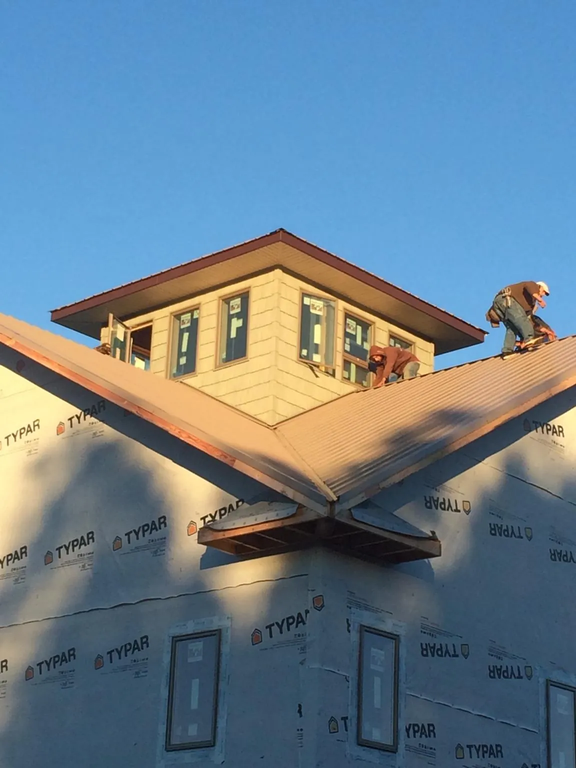 Roofers working around a rooftop cupola on a new metal roof at sunset — Roof Waterproofing in Gulf Shores by Roofing Brothers